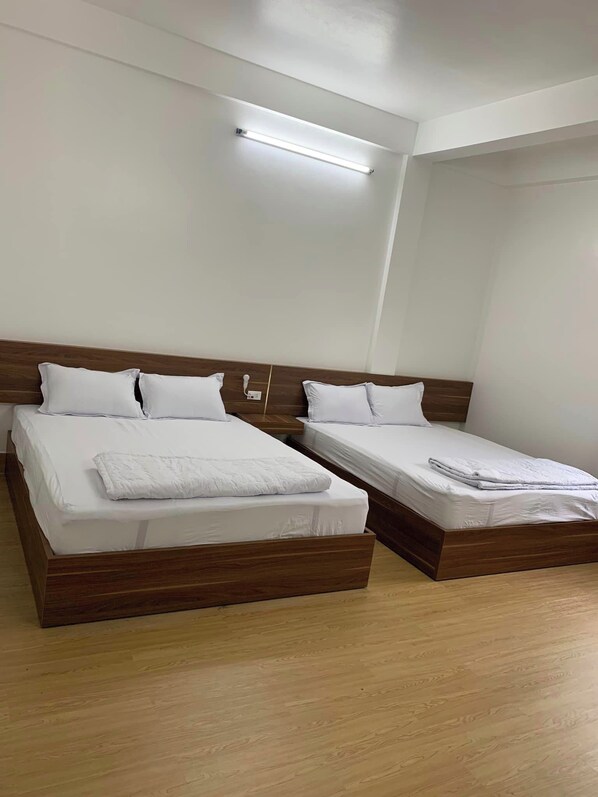 A hotel room with two wooden beds, white bedding, and a ceiling light. - Nha Nghi 68 (Rach Gia)