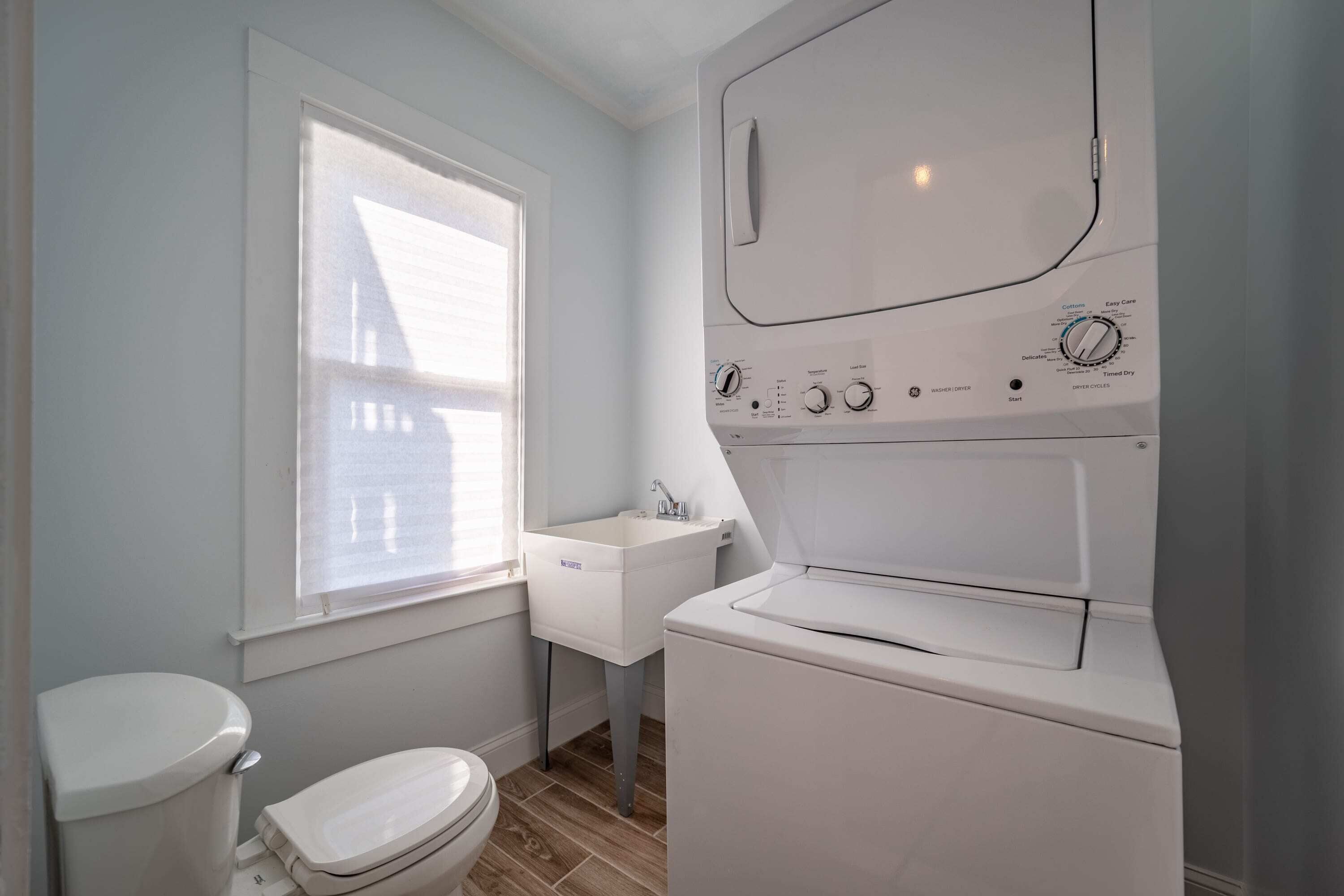 Een kleine badkamer met een toilet, een wastafel en een voorlader wasmachine.