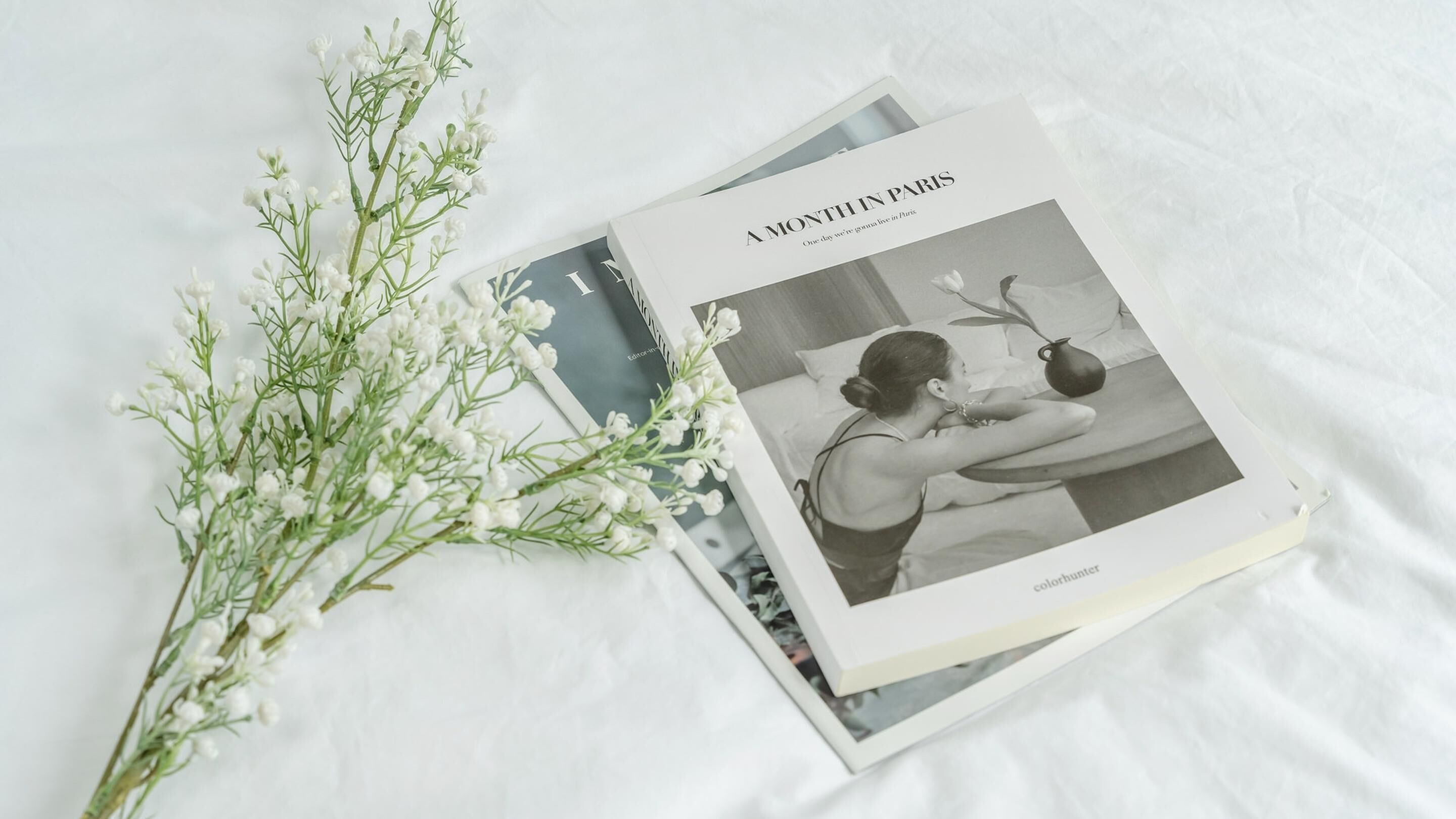 A magazine titled "A MONTH IN PARIS" with a black and white photograph of a person drinking from a jug.