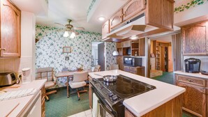 Una cocina con gabinetes de madera, estufa, microondas y un comedor con sillas y mesa.