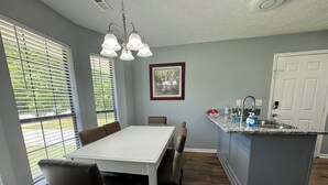 A dining area with a white table and chairs, a kitchen with a granite countertop, and a door. - Joyful Place 2 King Bed 2 bath
10 Min to Berry College, Shorter University (Rome)