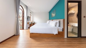 Ein modernes Hotelzimmer mit einem großen Bett, einem Badezimmer mit Waschbecken und Spiegel sowie einem Ausblick durch ein großes Fenster.