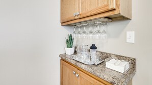 A kitchen with wooden cabinets, a granite countertop, a wine rack, a potted plant, a coffee maker, and a towel rack. - Pet-Friendly Pacific Cottage Near Purina Farms! (Pacific)