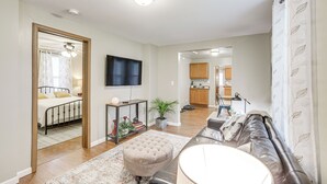 A modern living room with a sofa, ottoman, and a flat-screen TV mounted on the wall. - Pet-Friendly Pacific Cottage Near Purina Farms! (Pacific)