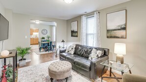 A living room with a leather sofa, ottoman, and glass coffee table. There is a dining area in the background with a blue table and chairs. - Pet-Friendly Pacific Cottage Near Purina Farms! (Pacific)