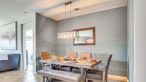 Een eethoek met een rechthoekige tafel, banken en stoelen. Daarboven hangt een lamp en aan de muur is een spiegel te zien.