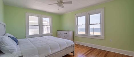 A bedroom with a bed, a nightstand, a dresser, and a ceiling fan.