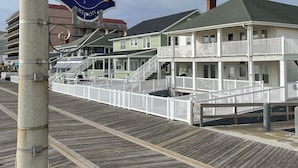 A boardwalk with a sign indicating the 11th location, adjacent buildings with balconies, and a wooden walkway. - OCHG SeaFoam Ocean Front5 (Ocean City)