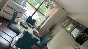 A dining area with a table and chairs, a chandelier, and a window with curtains.