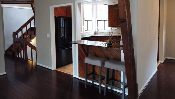 A spacious kitchen with a black refrigerator, wooden cabinets, and a window.