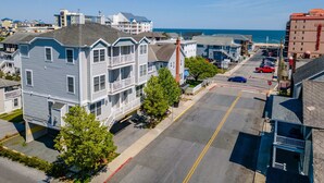 A coastal residential area with multi-story houses, a parking lot, and a view of the ocean. - OCHG Townhouse 102 10 (Ocean City)