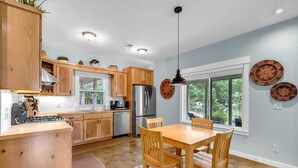 A modern kitchen with wooden cabinets, stainless steel appliances, and a dining area with a table and chairs.
