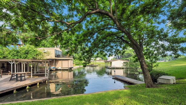 A serene lakeside property with a dock, a covered seating area, and a small building near the water.