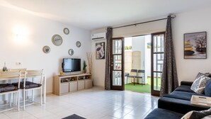 Un salon avec un téléviseur, un canapé et un coin repas comprenant des chaises et une table.