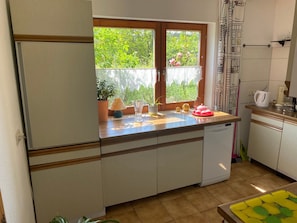A compact kitchen with a window, a refrigerator, a sink, and a countertop with various items.