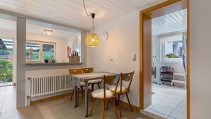 A dining area with a table, chairs, a hanging light fixture, and a view of the outside. - Apartment 'Fewo Max' with Shared Terrace, Balcony and Wi-Fi (Ettenheim Münchweier)