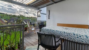 A balcony with a table and chairs, a view of the countryside, and a thermometer on the wall. - Apartment 'Fewo Max' with Shared Terrace, Balcony and Wi-Fi (Ettenheim Münchweier)