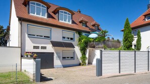 Ein zweistöckiges Haus mit Garage, überdachter Terrasse und einem eingezäunten Auffahrt.