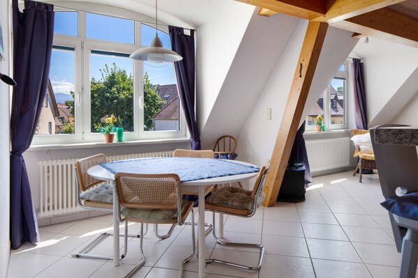 A dining area with a round table, chairs, and a view of the outside.