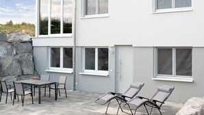 A two-story building with the name 'Bantlehof' on the facade, large windows, outdoor seating area with chairs, and a stone wall.
