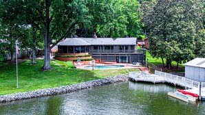 Une propriété située au bord d’un lac, dotée d’une piscine, d’un quai et d’un grand bâtiment avec un patio couvert.