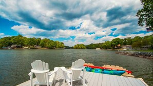 Une terrasse en bois avec des fauteuils Adirondack blancs et un kayak aux couleurs vives.