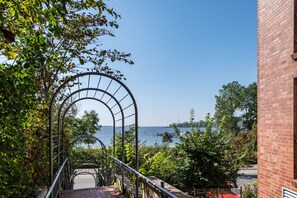 A staircase leading to a view of the sea, surrounded by greenery and a brick building. - Apartment 'Ferienwohnung Am Salzhaff B6' with Sea View, Balcony and Wi-Fi (Ostseebad Rerik)