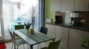 Una cocina con una mesa de comedor, sillas, una cafetera y vistas al exterior.