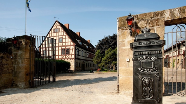 A traditional half-timbered building with a stone gate and a street lamp.