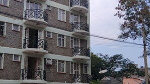 A multi-story building with balconies, brick facade, and multiple windows. - shammah hotel ltd (Kisumu)