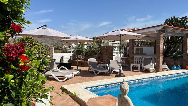 Un espace aménagé au bord de la piscine, avec des chaises longues, des parasols et une statue de Bouddha.