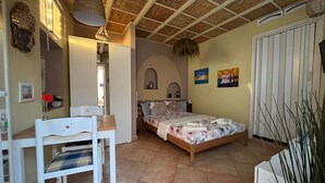 Une chambre à coucher comprenant un lit, un bureau, une chaise, une armoire et un ventilateur de plafond.