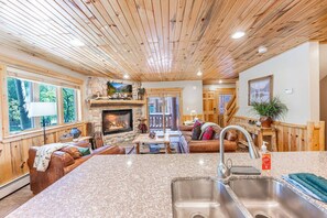 Un intérieur de chalet chaleureux avec une cheminée, un plafond en bois et un manteau de cheminée en pierre.