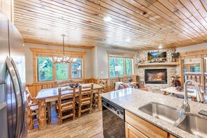 Une cuisine avec une cheminée en pierre, un plafond en bois et de grandes fenêtres.