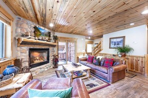 A cozy interior with a fireplace, leather furniture, and a stone wall. - Timber Wolf 6B (Park City)