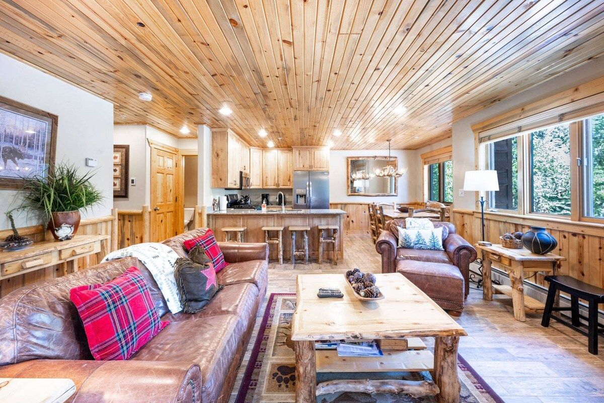 A cozy interior with a wooden ceiling, a kitchen area, and seating arrangements.