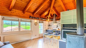Una cocina amplia con vigas de madera, un ventanal grande y una estufa empotrada.