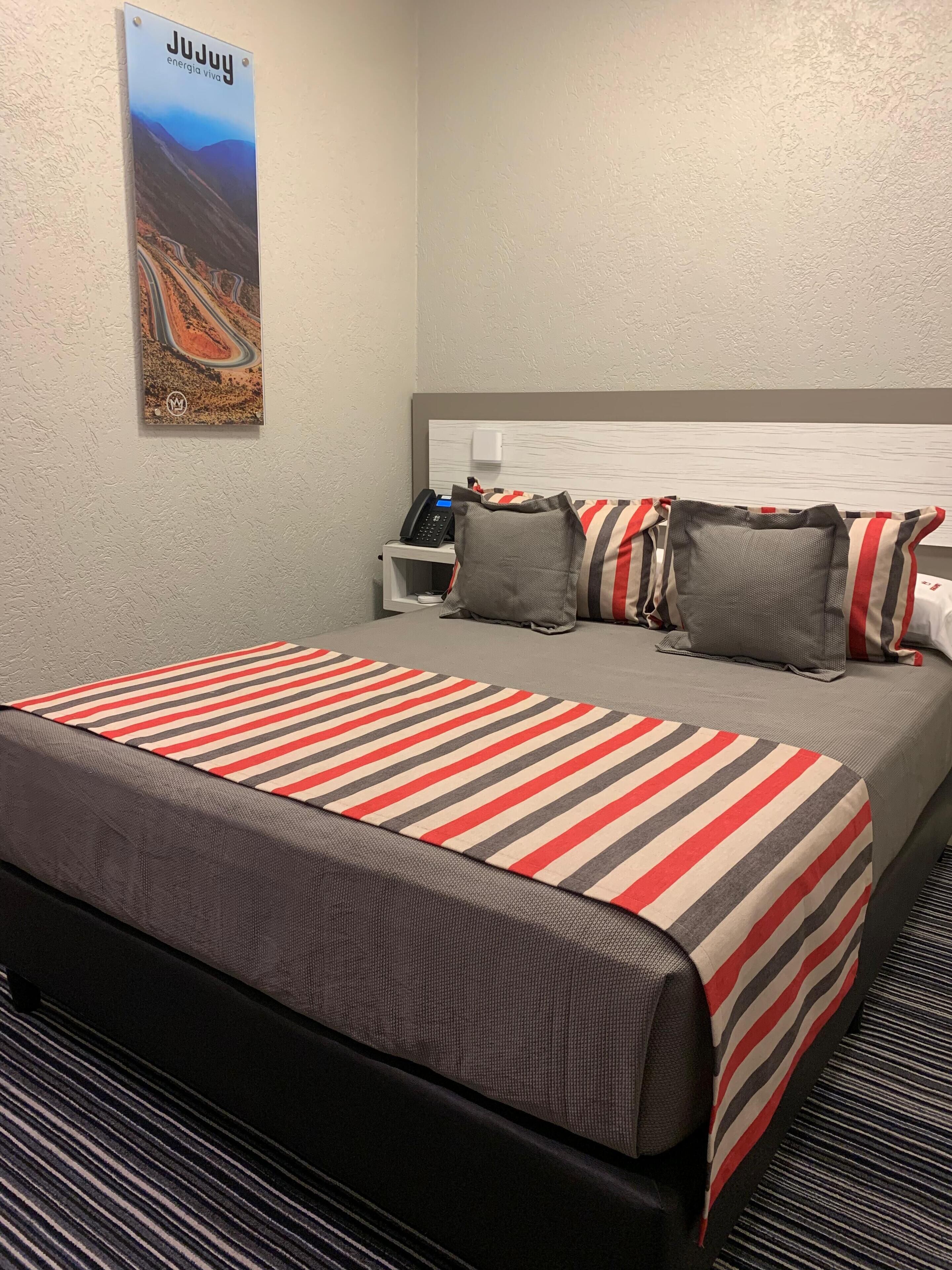 Una habitación de hotel con una cama, una mesita de noche, un teléfono y un cartel en la pared.