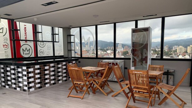 Un interior moderno con una pared a cuadros, muebles de madera y ventanas amplias que ofrecen vistas a la ciudad.
