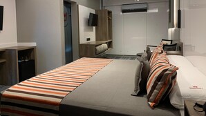 Una habitación de hotel moderna con cama, televisor, armario y escritorio.