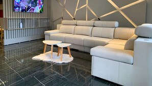 Una sala moderna con un sofá modular, un televisor de pantalla plana y un diseño geométrico en la pared.