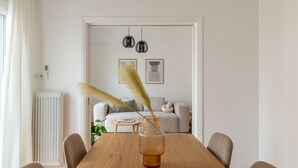 Et spiseområde med et træbord, stole og en vase med pampasfjer.