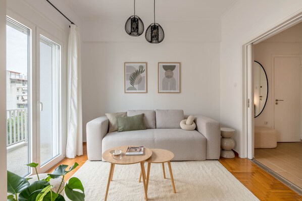 En moderne stue med sofa, to sofaborde, et stort vindue og udsigt ud