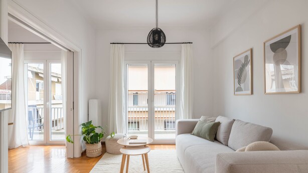 En moderne stue med en sofa, et rundt bord og en potteplante.