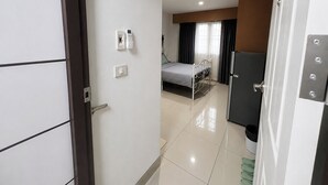 Una habitación de hotel con cama, escritorio, silla, armario y puerta.