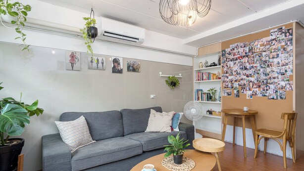 Una sala de estar moderna con un sofá gris, una mesa de centro de madera y una pared decorada con fotografías.