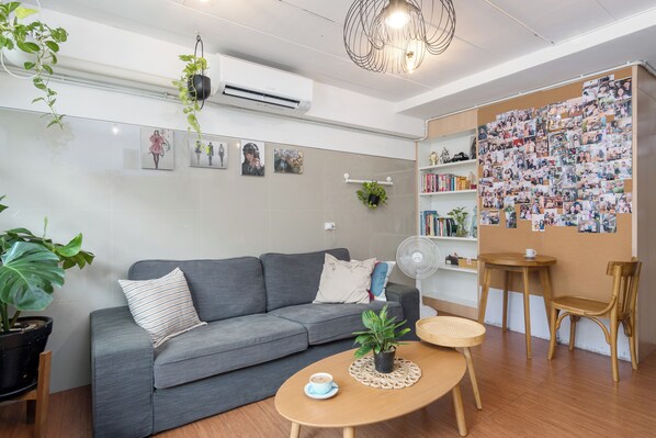 Un saló modern amb un sofà gris, una taula de centre de fusta i una paret decorada amb fotos.