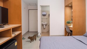Un dormitorio con una cama, un escritorio, un televisor y un gato.