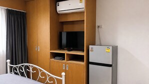 Un dormitorio con cama, armario, televisor y refrigerador.