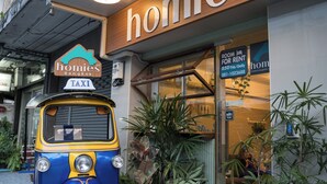 Un taxi estacionado frente a un edificio con un letrero que dice "homies" y un cartel de "Habitación para alquilar".